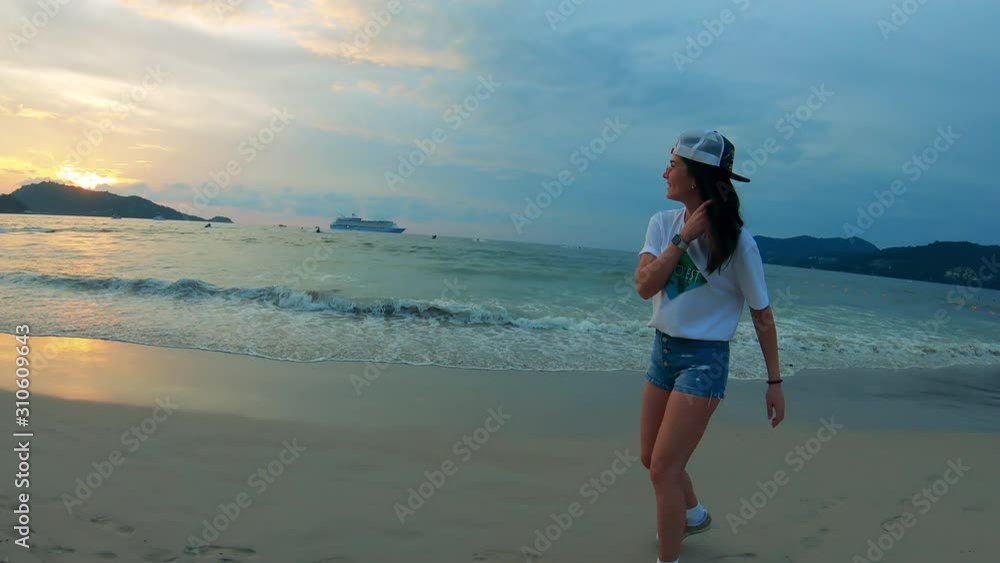 Young woman in summer clothes is walking along the shore Young woman in summer clothes is walking along the shore
