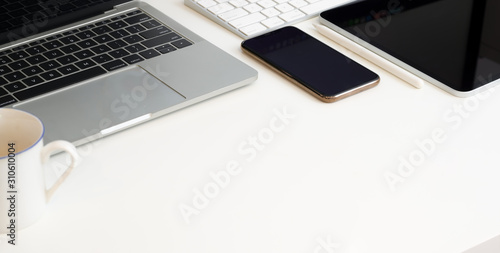 Cropped shot of trendy workplace with laptop computer na office supplies on white table
