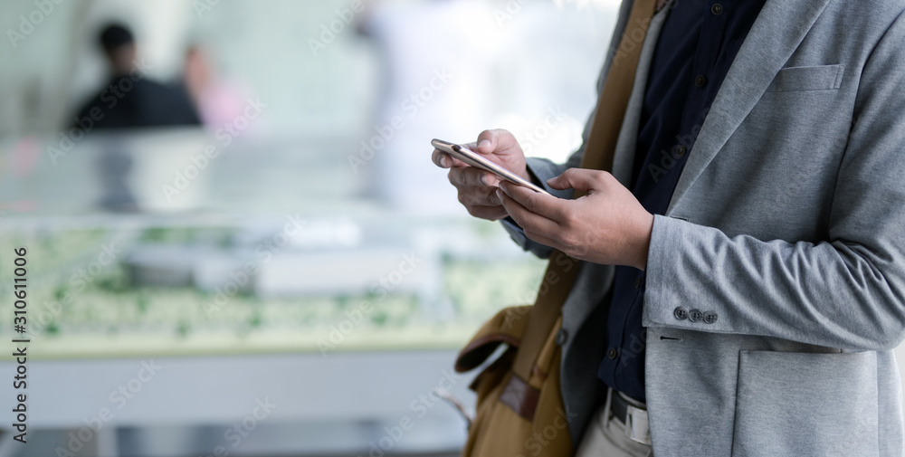 Close-up view of young businessman using smartphone with blurred office room