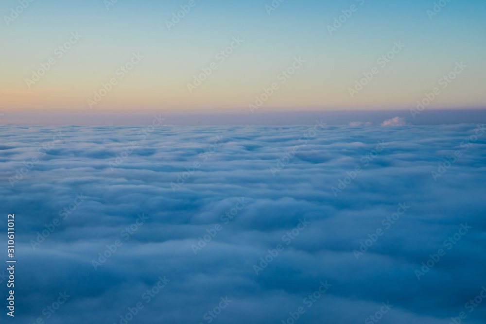 Endless aerial view above fluffy clouds at sunset from the top of a mountain in winter, a beautiful nature landscape