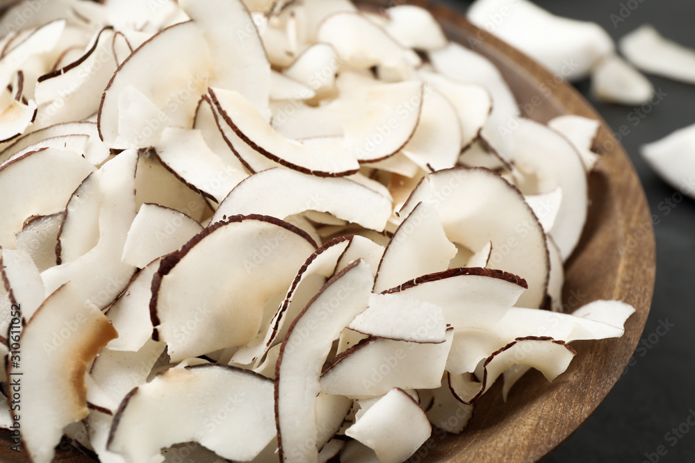 Tasty coconut chips in wooden bowl, closeup Tasty coconut chips in wooden bowl, closeup