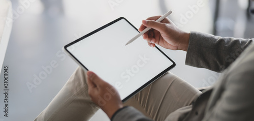 Close-up view of young businessman using blank screen tablet while working