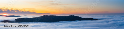 Germany, XXL panorama aerial view above endless fog clouds surrounding teckberg mountain and castle teck at sunset in winter