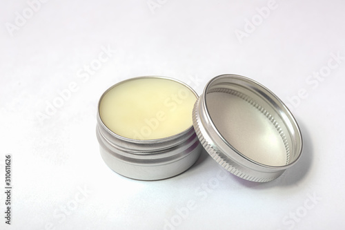 Lip balm in the round metallic tins on the white background