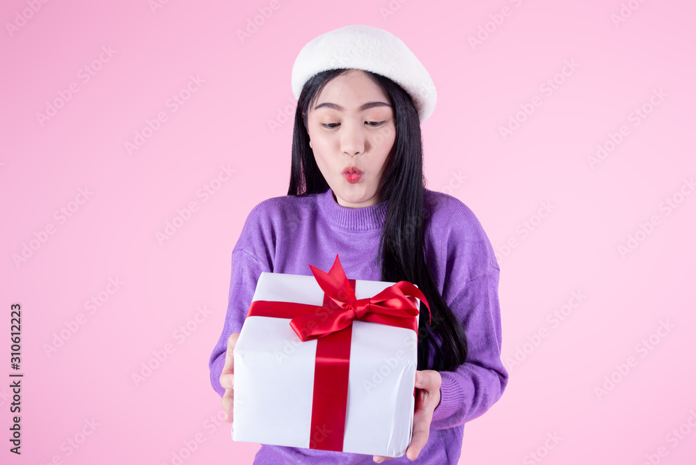 Surprising Asian woman wearhing purple sweater holding gift box on pink background. Surprising Asian woman wearhing purple sweater holding gift box on pink background.
