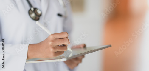 Cropped shot fo young female doctor working on medical records and exam results with tablet