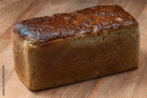 rectangular loaf of wheat bread with a baked shiny crust on the kitchen table.