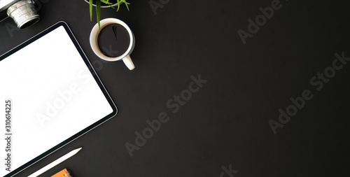 Top view of trendy photographer workplace with blank screen tablet and office supplies on black table