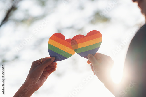 Close up hand of LGBTQ couple holding rainbow heart.
