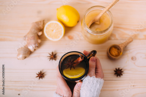 Close up of female hands holding cup of warm water with lemon photo