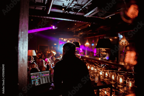 DJ with headphones at night club party under the blue light and people crowd in background © Семен Саливанчук