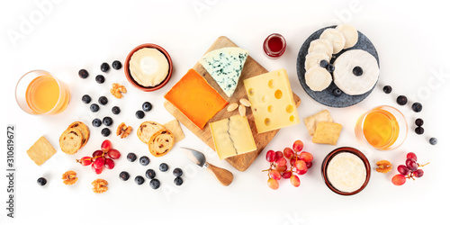 Cheese board, a flat lay panorama on a white background. Blue cheese, red Leicester, Emmental, goat cheese, Brie and others, shot from the top with wine and fruits