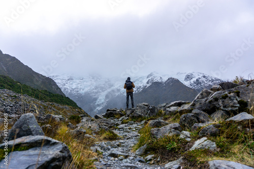 Fototapeta Naklejka Na Ścianę i Meble -  A man hiking mount cook under cloudy sky in New Zealand