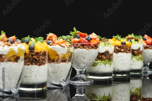 selective focus of fresh granola with fresh fruits and berries isolated on black