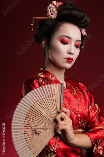 Fotografia Image of young geisha woman in japanese kimono holding wooden hand fan