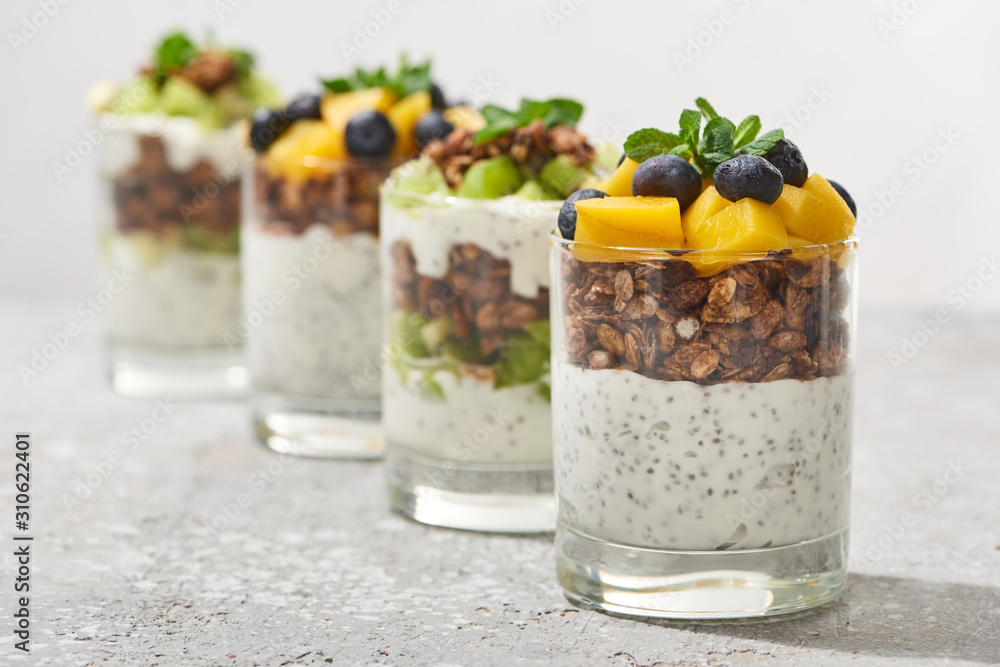 selective focus of fresh granola with kiwi and canned peach with blueberries on grey concrete surface isolated on grey selective focus of fresh granola with kiwi and canned peach with blueberries on grey concrete surface isolated on grey