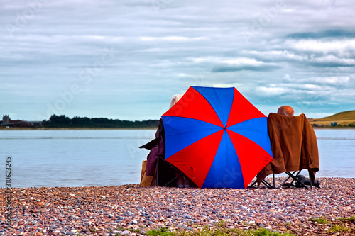 Couple sitting on the coast watching for dolphins at Chanonry Point on the Cromarty Firth in the Highlands of Scotland