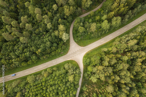 Road with car and intersection through forest from above