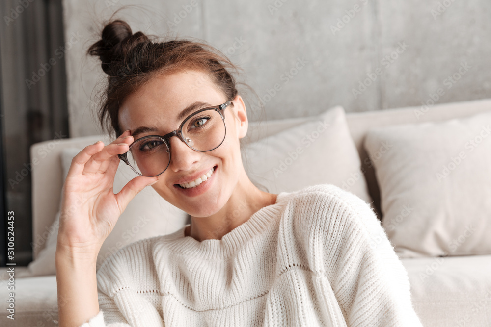 Image of woman in eyeglasses smiling while resting on sofa at home Image of woman in eyeglasses smiling while resting on sofa at home