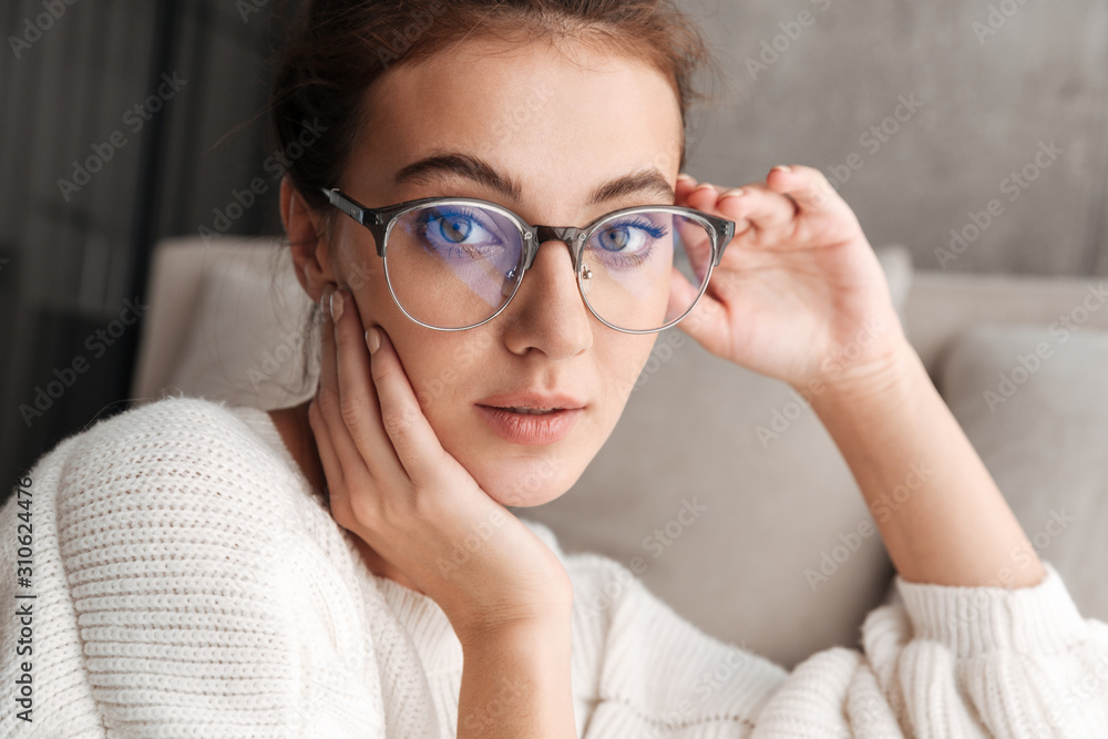 Image of lovely young woman in eyeglasses resting on sofa at home Image of lovely young woman in eyeglasses resting on sofa at home