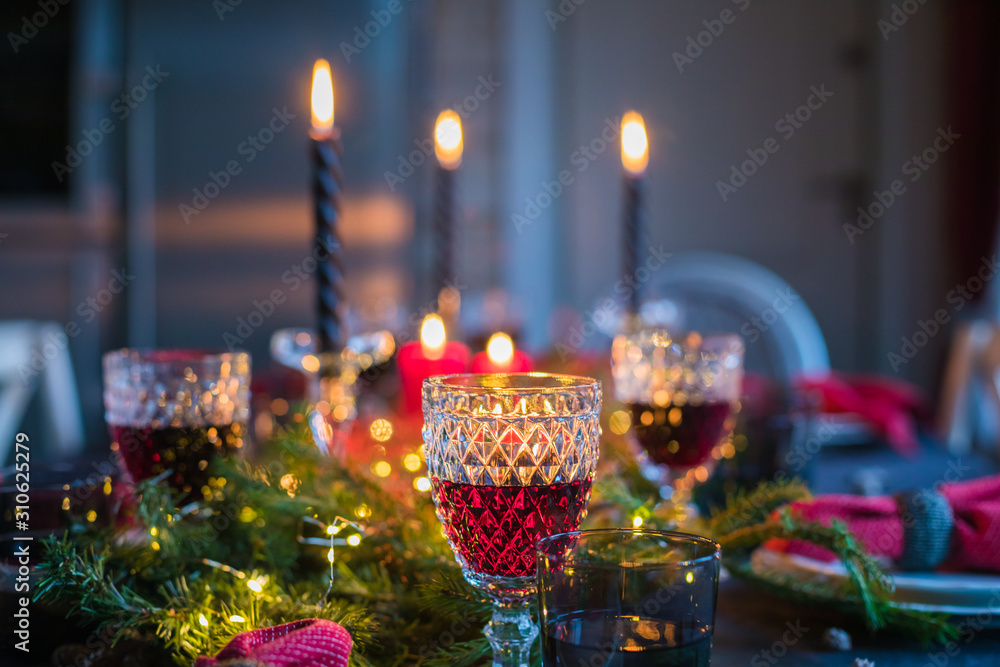 Fototapeta premium Table served for Christmas dinner, festive setting with decorations, burning candles and fir-tree branches