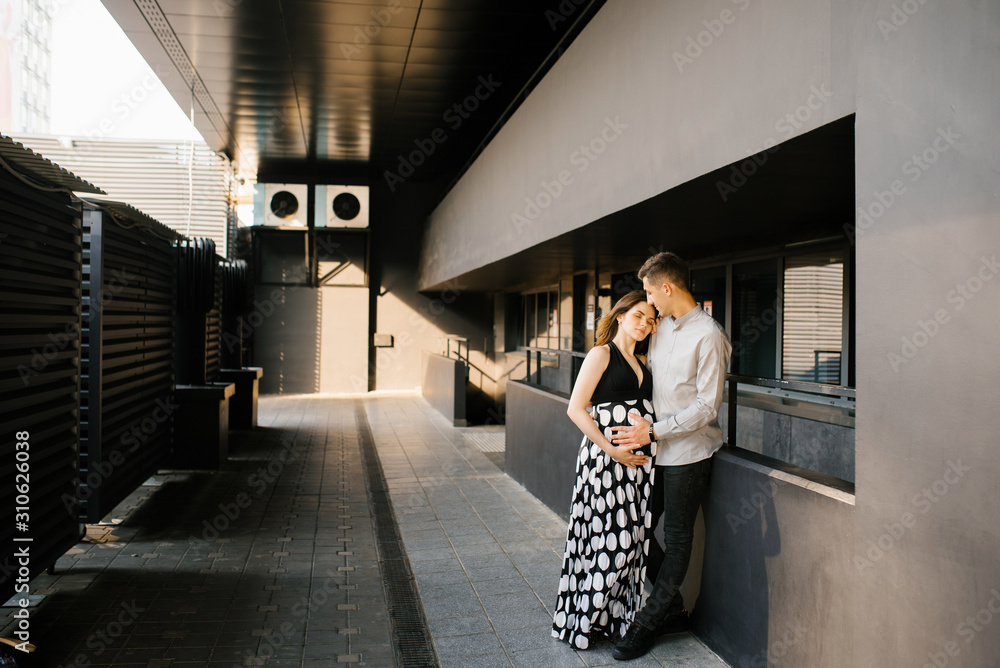 The parents are walking around the city, cuddling and enjoying the anticipation of your baby - obrazy, fototapety, plakaty 