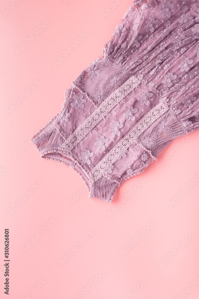 Girls' fashion background, lace dress in lilac on pink table, flat lay, top view, copy space for text, selective focus