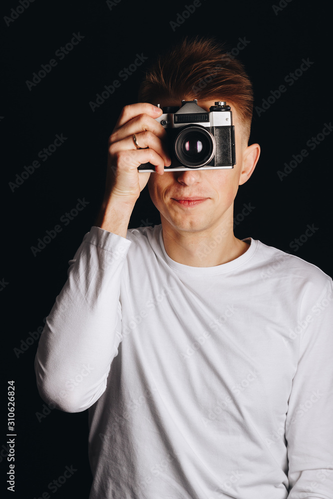 Cheerful guy with a retro camera on a black background Cheerful guy with a retro camera on a black background