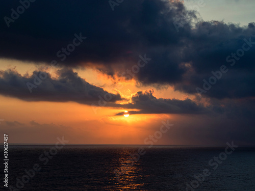 The sun between the dark gray clouds on the sea