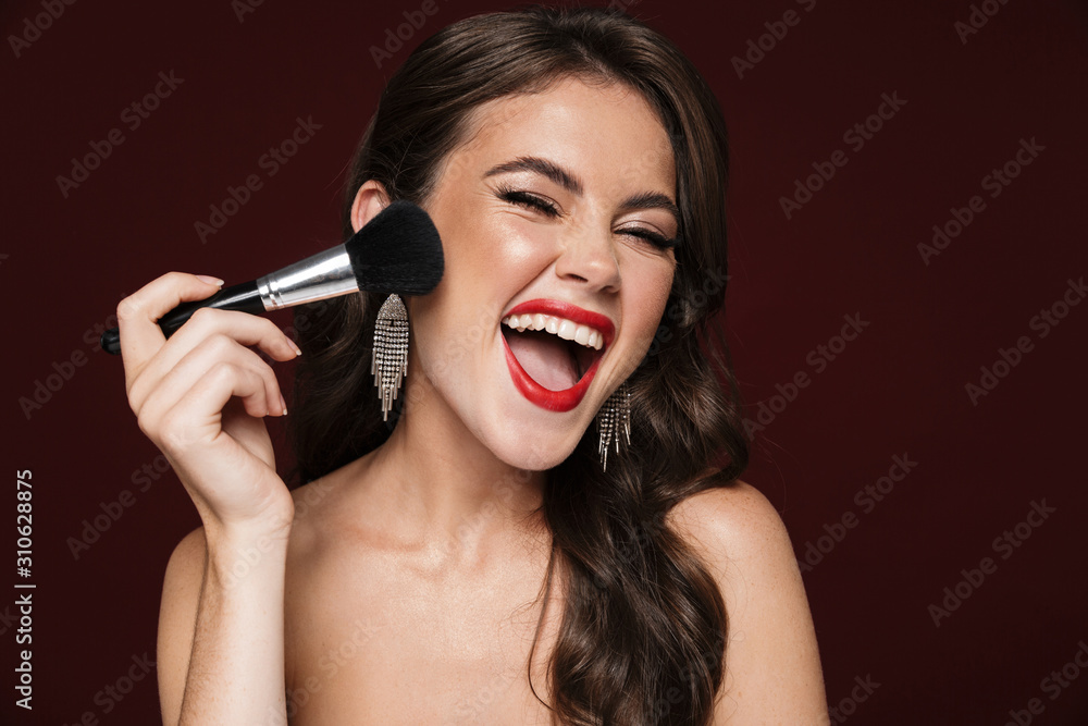 Image of excited shirtless woman laughing and using powder brush Image of excited shirtless woman laughing and using powder brush