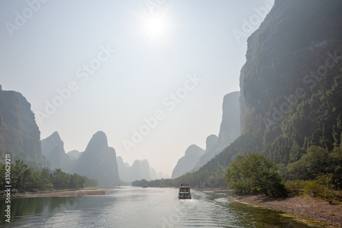 Boat on Li river cruise and karst formation mountain landscape in the fog between Guiling and Yangshuo  Guangxi province  China