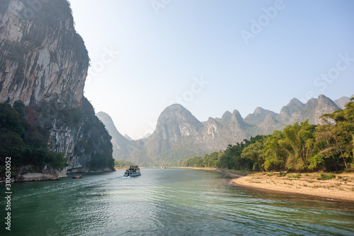 Boat on Li river cruise and karst formation mountain landscape in the fog between Guiling and Yangshuo, Guangxi province, China photo