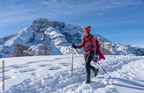 active senior woman snowshoeing from Prato Piazzo up to the Monte Specie in the three oeaks Dolomites area near village of Innichen, South Tyrol, Italy photo