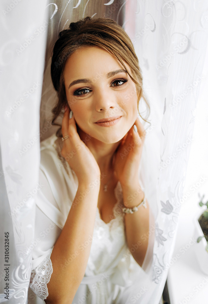 Portrait of a pretty bride in a peignoir standing by the window Portrait of a pretty bride in a peignoir standing by the window