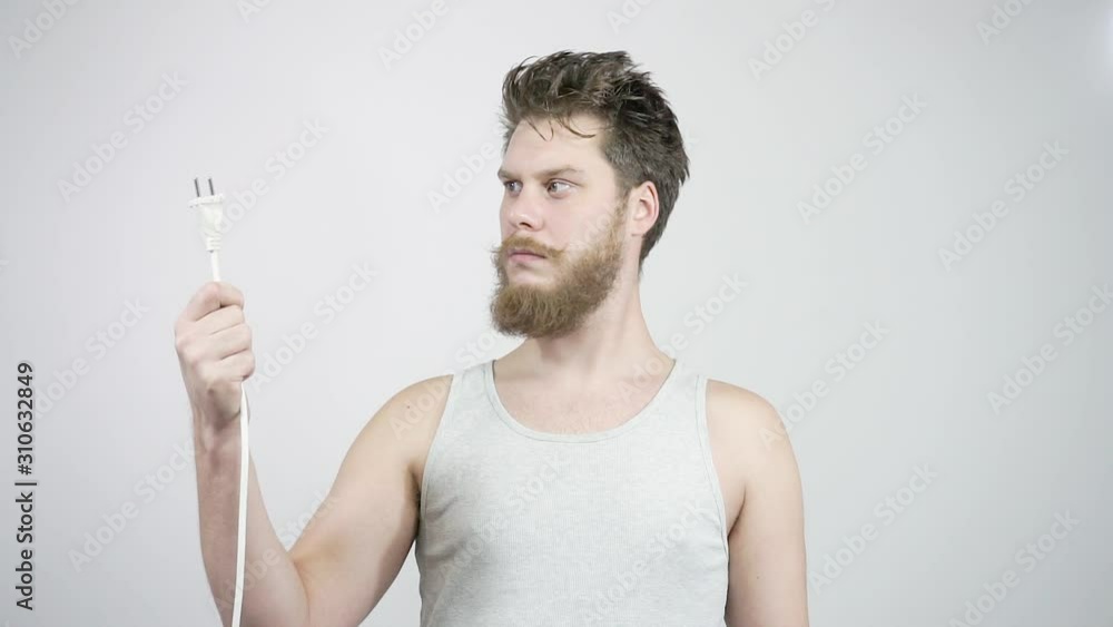 The bearded guy looks at the cable plug. Surprise home electrician The bearded guy looks at the cable plug. Surprise home electrician