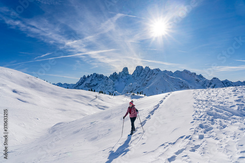 active senior woman snowshoeing from Prato Piazzo up to the Monte Specie in the three oeaks Dolomites area near village of Innichen, South Tyrol, Italy
