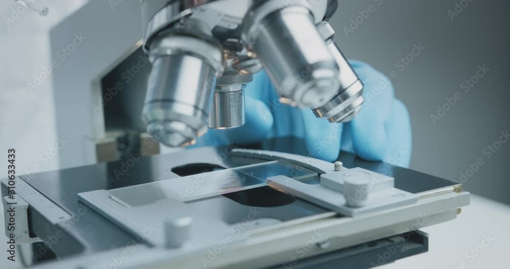 Close up shot of the scientist studies examining of test sample under the microscope in laboratory. Close up shot of the scientist studies examining of test sample under the microscope in laboratory.