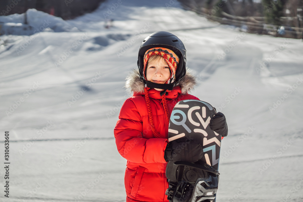 Little cute boy is ready for snowboarding. Activities for children in winter. Children's winter sport. Lifestyle Little cute boy is ready for snowboarding. Activities for children in winter. Children's winter sport. Lifestyle