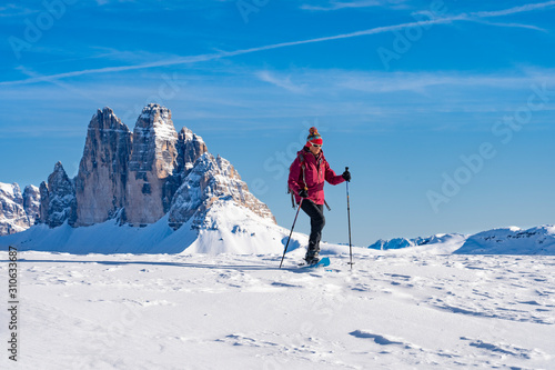 active senior woman snowshoeing under the famous Three Peaks from Prato Piazzo up to the Monte Specie in the three oeaks Dolomites area near village of Innichen, South Tyrol, Italy