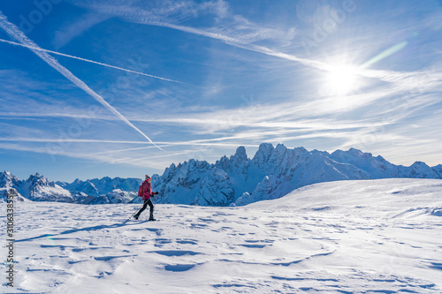 active senior woman snowshoeing under the famous Three Peaks from Prato Piazzo up to the Monte Specie in the three oeaks Dolomites area near village of Innichen, South Tyrol, Italy photo