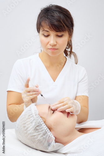 doctor-cosmetician carries out medical treatment injecting gel-like medicine under skin in beauty clinic