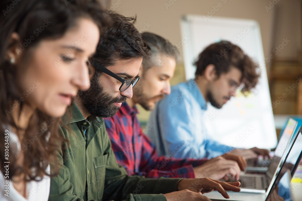 Line of coworkers using laptops in training room or class. Business colleagues in casual working together in contemporary office space. Workplace concept Line of coworkers using laptops in training room or class. Business colleagues in casual working together in contemporary office space. Workplace concept