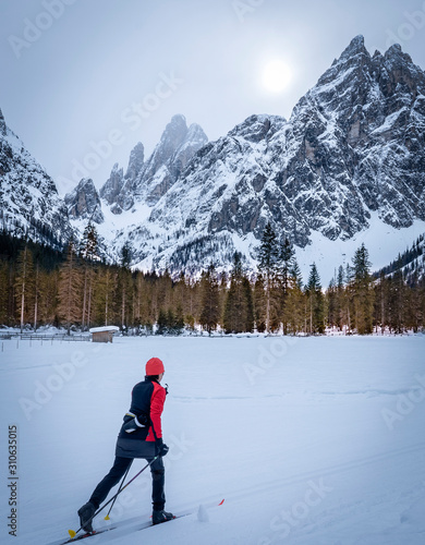 active senior woman on her cross country skis on ski track in the Fischlein Valley, Three peak Dolomites, South Tyrol, Italy photo