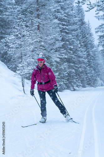 active senior woman on her cross country skis on ski track in the Fischlein Valley, Three peak Dolomites, South Tyrol, Italy photo