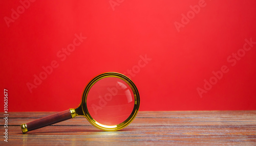 Magnifying glass on a red background. Search and analysis, analytics and study. Pay attention to details and problems. Find something. Journalistic investigations and research. Search tool