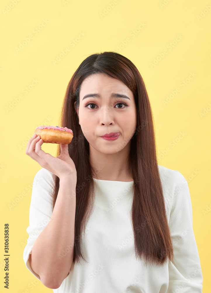 Close up portrait of a cute girl posing with donuts on yellow background Close up portrait of a cute girl posing with donuts on yellow background