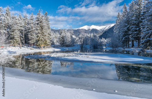 landscape photography on cold winter morning at sunrise at partly frozen Lago Dobbiaco, Dolomites, Three Peaks Dolomites, South Tyrol, Italy