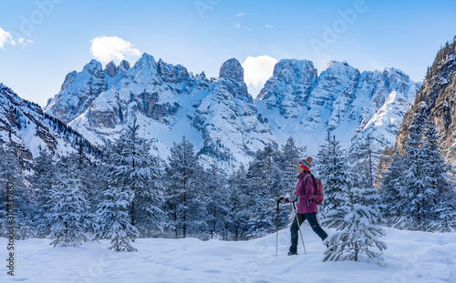 active senior woman snowshoeing in spectacular Hoehlenstein Valley under the Monte Crstallo, Dolomites near village of Toblach, South Tyrol, Italy