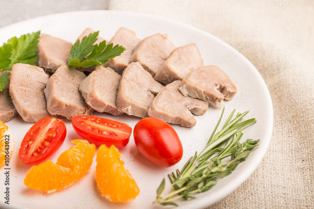 Boiled pork tongue with tomatoes and herbs on a gray concrete background. Side view, selective focus. Boiled pork tongue with tomatoes and herbs on a gray concrete background. Side view, selective focus.