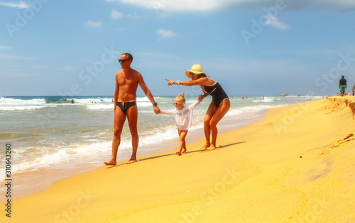 dad and mom show something far away for little daughter, sandy beach, tropics, resort vacation